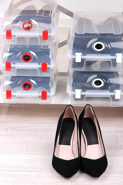 Zapatos en cajas de plástico y zapatos femeninos en el piso en la habitación —  Fotos de Stock