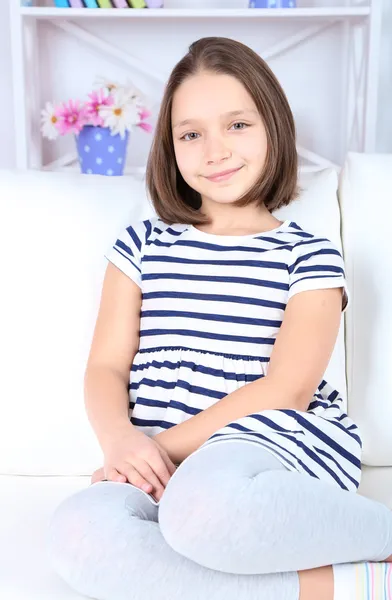 Hermosa niña sentada en el sofá, en el fondo interior de casa — Foto de Stock