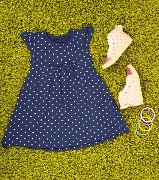 Hermoso vestido y zapatos de goma para niña en la alfombra verde — Foto de Stock