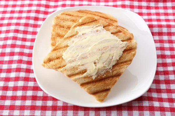 Grilled bread with butter on tablecloth — Stock Photo, Image
