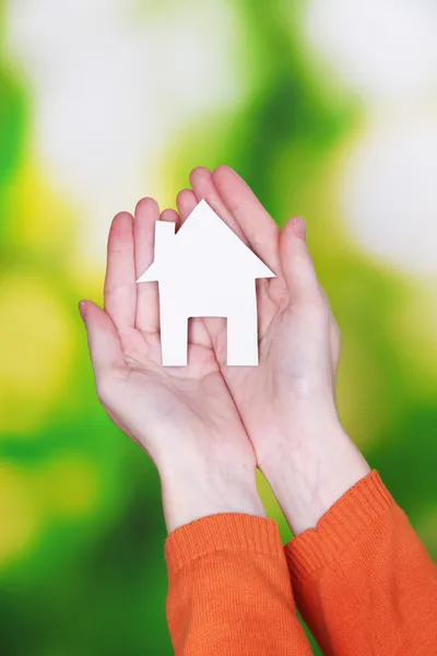 Papierhäuschen in der Hand in Nahaufnahme, auf hellem Hintergrund — Stockfoto