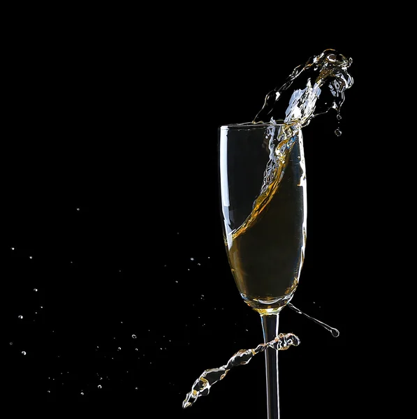 Glass of champagne with splash, on black background — Stock Photo, Image