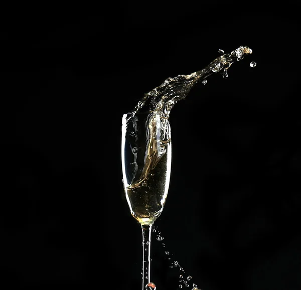 黒の背景にスプラッシュとシャンパンのグラス — ストック写真