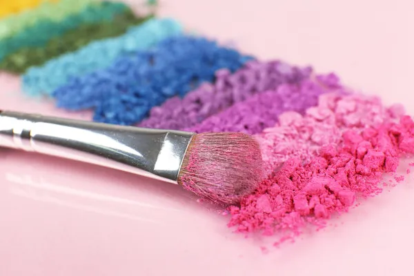 Arco-íris esmagado sombra e escova de maquiagem profissional no fundo rosa — Fotografia de Stock