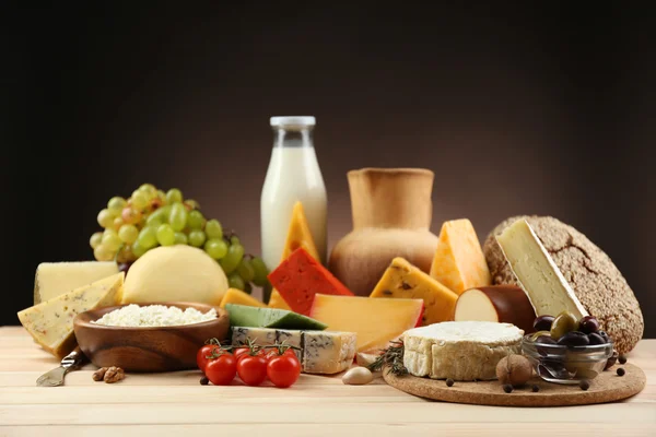 Tasty dairy products on wooden table, on dark background — Stock Photo, Image