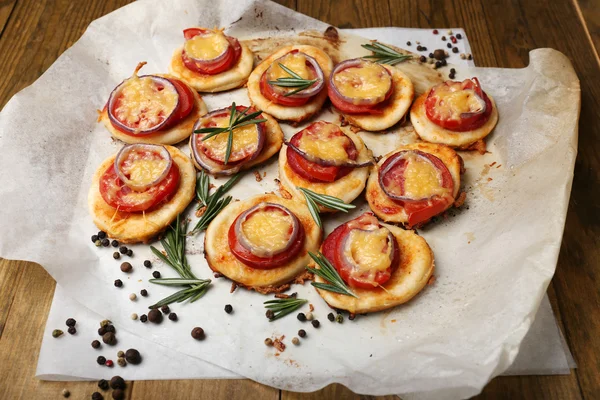 Small pizzas on baking paper close up — Stock Photo, Image