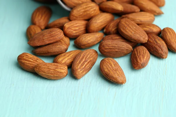 Almonds in bucket on color wooden background — Stock Photo, Image