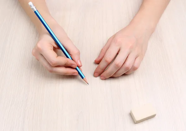 Mänskliga händer med penna och radera gummi på träbord bakgrund — Stockfoto
