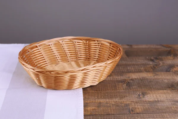 木制的桌子，在深色背景上的空的柳条篮子 — 图库照片