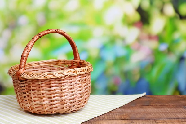 Lege rieten mand op houten tafel, op lichte achtergrond — Stockfoto