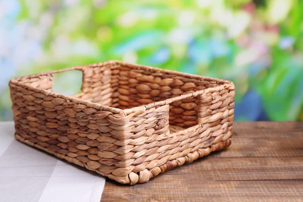 Panier en osier vide sur table en bois, sur fond lumineux — Photo