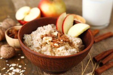 Tasty oatmeal with nuts and apples on wooden table clipart