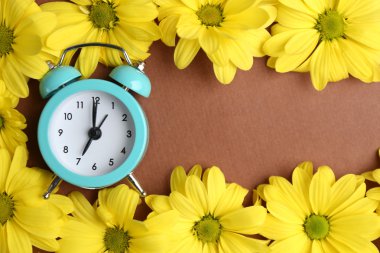 çalar saat ve kahverengi zemin üzerine güzel çiçekler