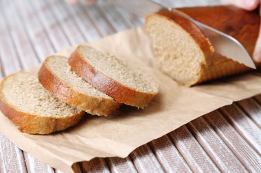 Ahşap tahtada ekmek kesen kadın elleri, yakın plan.