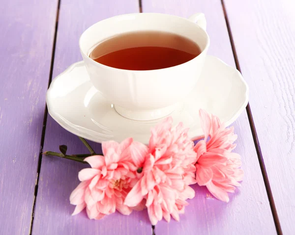 Crisantemos rosados y taza de té sobre mesa de madera — Foto de Stock