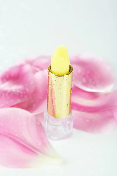 Hygienic lipstick with petals isolated on white — Stock Photo, Image