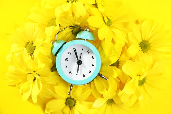 Reloj despertador y hermosas flores sobre fondo amarillo —  Fotos de Stock