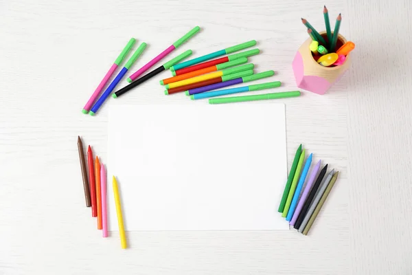 Colored pencils and blank paper sheet on wooden table — Stock Photo, Image