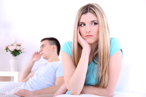 Конфликт между молодым человеком и женщиной, сидя на диване, спорить недовольны, на домашнем фоне интерьера
