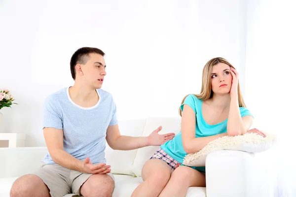 Young man and woman  conflict sitting on sofa argue unhappy, on home interior background — Stock Photo, Image