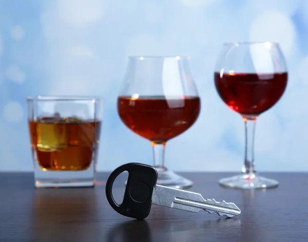 Composição com chave de carro e copos de bebidas, na mesa de madeira, no fundo brilhante — Fotografia de Stock