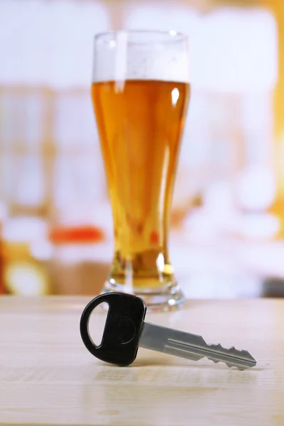 Composition avec clé de voiture et verre de bière, sur table en bois, sur fond lumineux — Photo