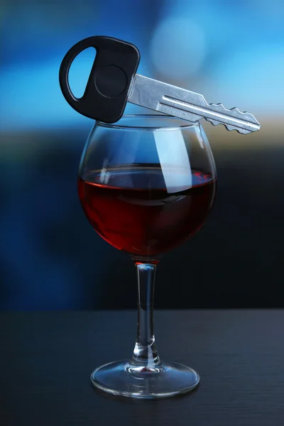 Composición con llave de coche y copa de vino tinto, sobre mesa de madera, sobre fondo brillante — Foto de Stock
