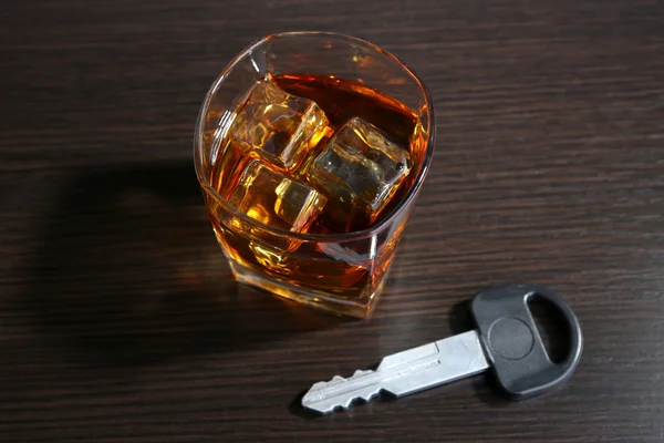 Композиція з автомобільним ключем і склянкою віскі на дерев'яному фоні — стокове фото