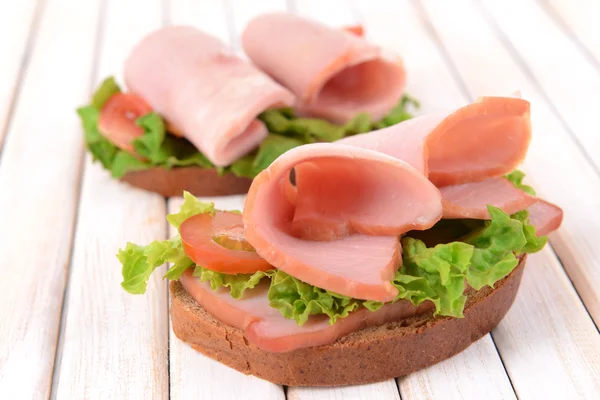 Heerlijke sandwiches met sla en ham op tafel close-up — Stockfoto