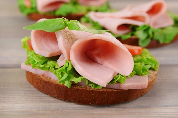 Heerlijke sandwiches met sla en ham op tafel close-up — Stockfoto
