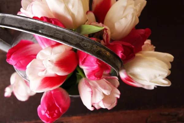 Krásné tulipány v konev na dřevěné pozadí — Stock fotografie