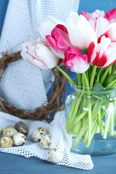 Složení s velikonoční vajíčka a krásné tulipány ve skleněné konvici na barevné dřevěné pozadí — Stock fotografie