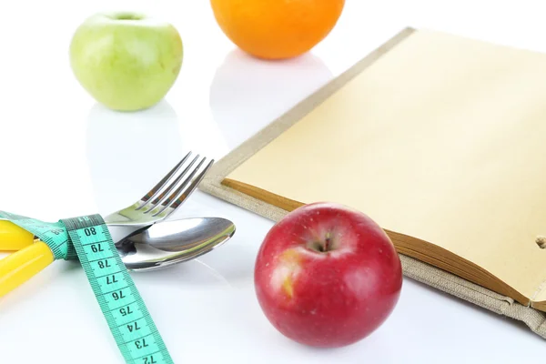 Talheres amarrados com fita métrica e livro com frutas isoladas em branco — Fotografia de Stock