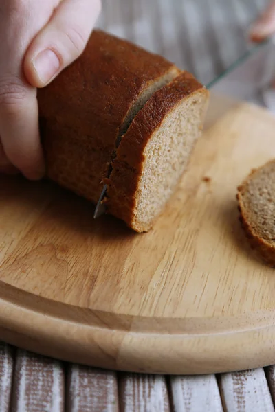 Руки женщины режут хлеб на деревянной доске, крупным планом — стоковое фото