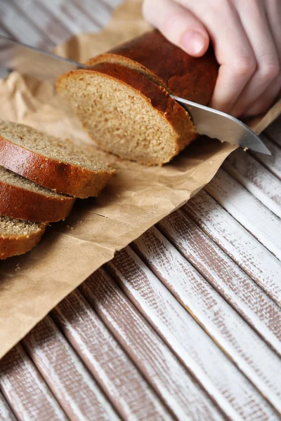 Руки женщины режут хлеб на деревянной доске, крупным планом — стоковое фото