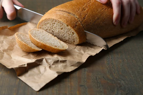 木の板にパンを切る女性の手、クローズアップ — ストック写真