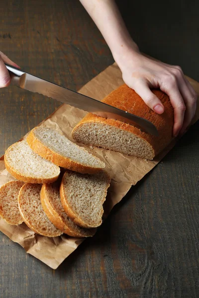 Female hands cutting bread on wooden board, close-up — Stock Photo, Image