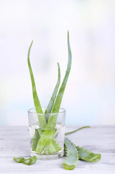 Färska gröna aloe lämnar i glas på träbord — Stockfoto
