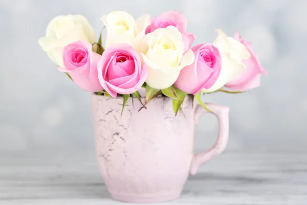 Beautiful roses in cup on light background — Stock Photo, Image