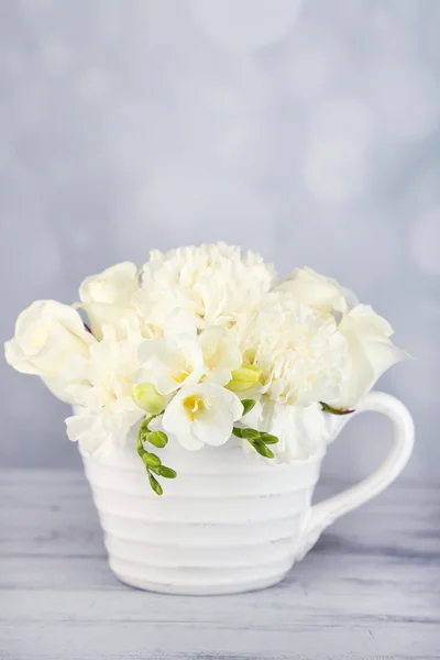 Прекрасные весенние цветы в чашке на светлом фоне — стоковое фото