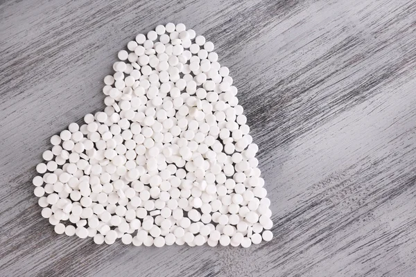 Heart of pills on wooden background — Stock Photo, Image
