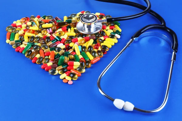 Heart of pills and stethoscope on blue background — Stock Photo, Image