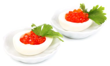 Red caviar in eggs on little white saucers isolated on white clipart