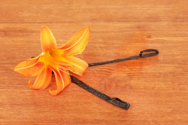 Vanilla pods with flower on wooden background — Stok fotoğraf