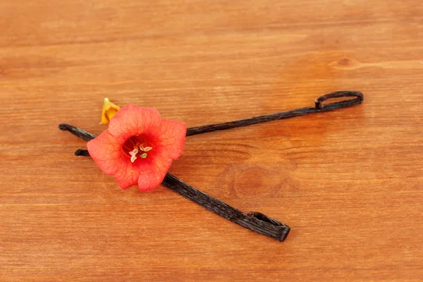 Vanilla pods with flower on wooden background — Stok fotoğraf