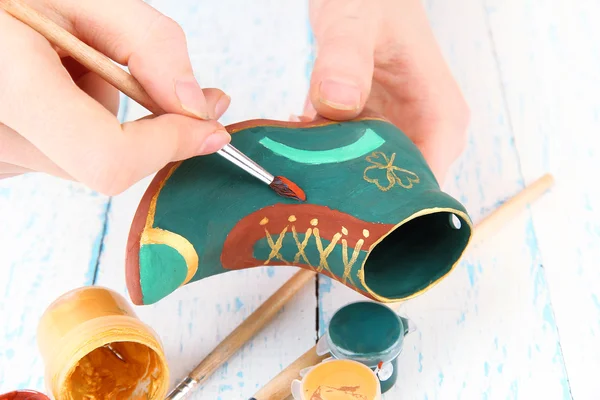 Hands paints on and made ceramic saint patricks day boot and art materials — Stock Photo, Image