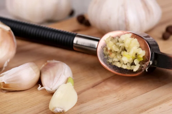 Knoflook druk op houten plank op lichte achtergrond — Stockfoto