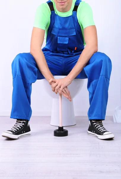 Plumber with toilet plunger on light background — Stock Photo, Image