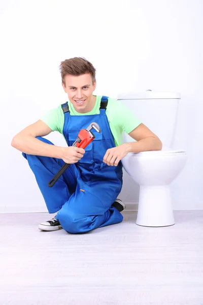 Plumber with toilet plunger on light background — Stock Photo, Image