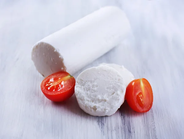 Tasty bushe cheese with tomato, on wooden table — Stock Photo, Image